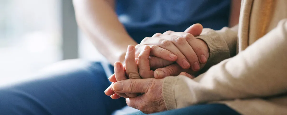 A SYNERGY HomeCare caregiver gently holding an elderly client's hands: continuous around-the-clock care