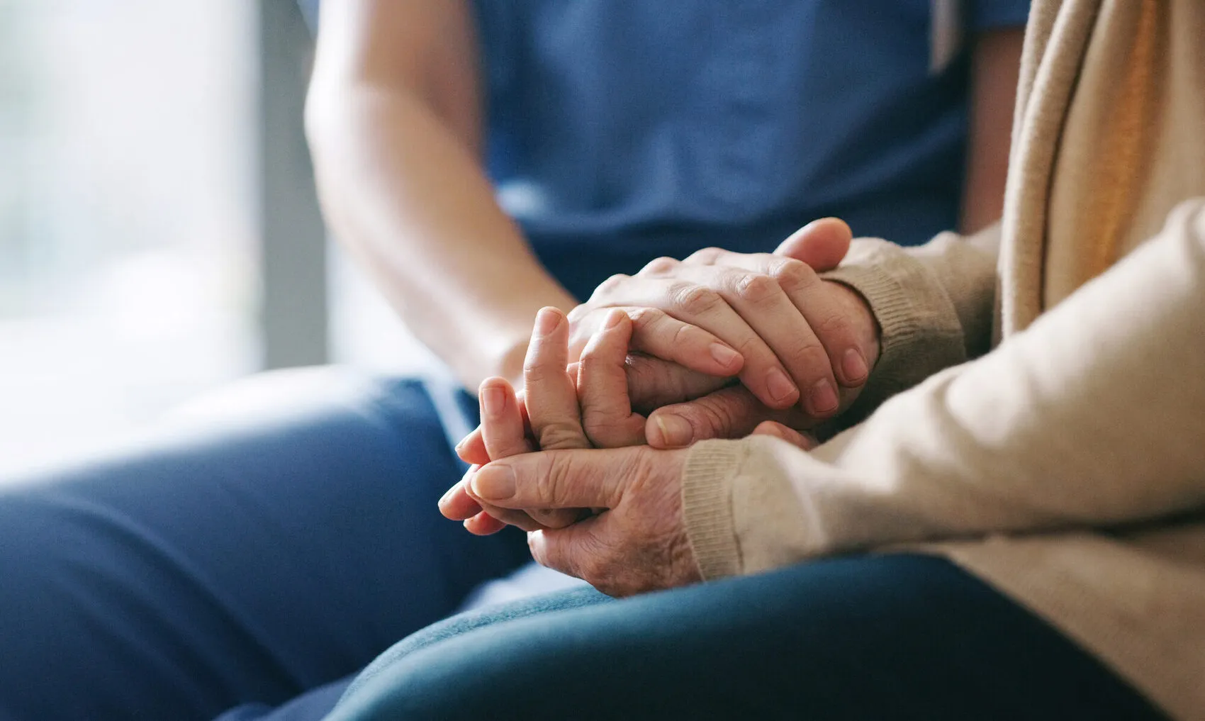 Close-up of home caregiver gently holding an elderly client's hands, a warm moment of comfort