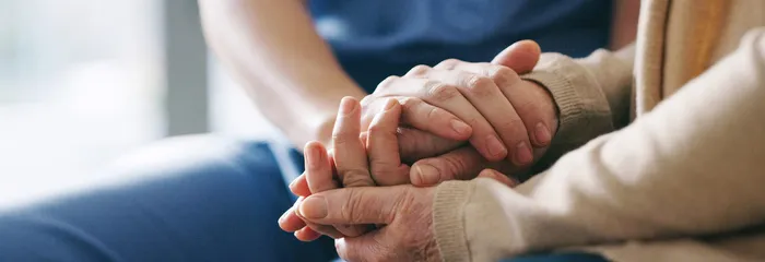 A SYNERGY HomeCare caregiver gently holding an elderly client's hands: continuous around-the-clock care