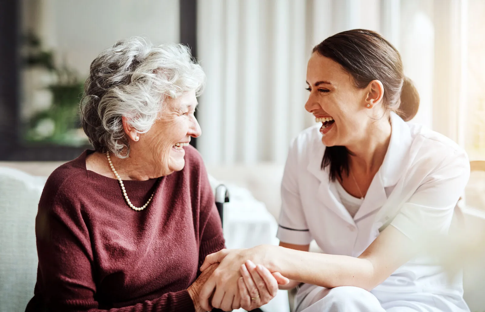 A SYNERGY HomeCare caregiver smiling and talking warmly with a senior woman during a home visit