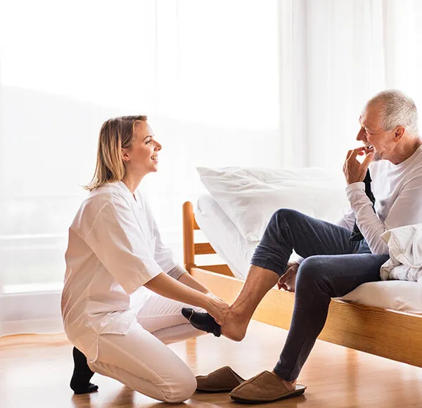 A SYNERGY HomeCare caregiver carefully helping a senior on the steps at home
