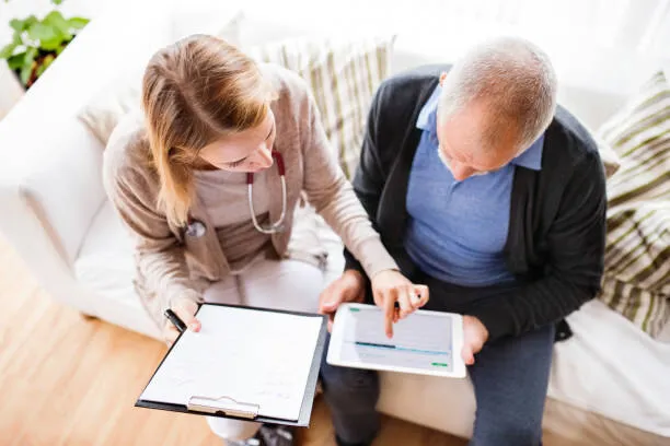 A SYNERGY HomeCare caregiver reviewing paperwork with a senior at a table while talking through a home care plan and its costs