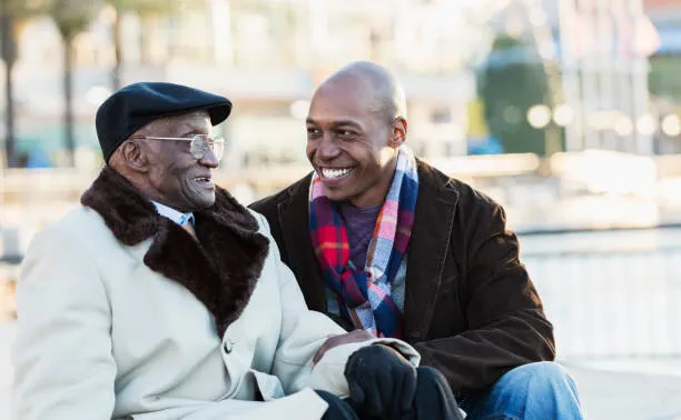 A SYNERGY HomeCare caregiver talking warmly with a senior Veteran outdoors